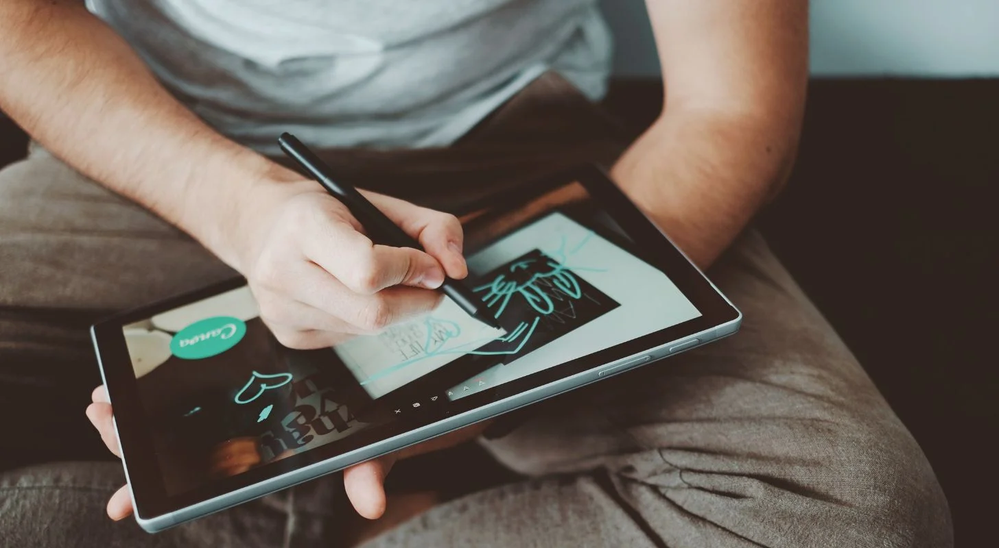 Man working on tablet with pencil in Canva program